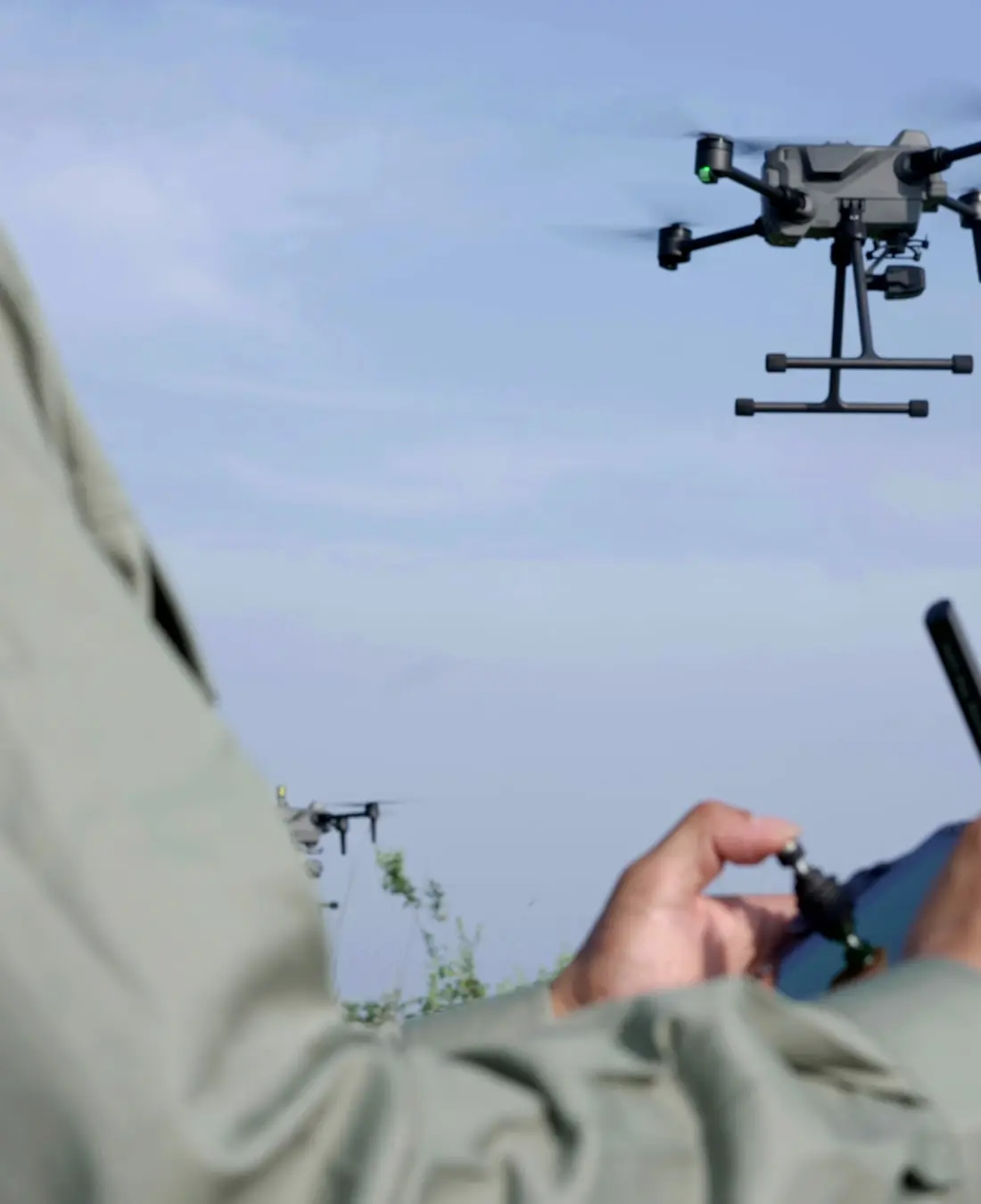 An operator holding a remote controller while a drone hovers overhead