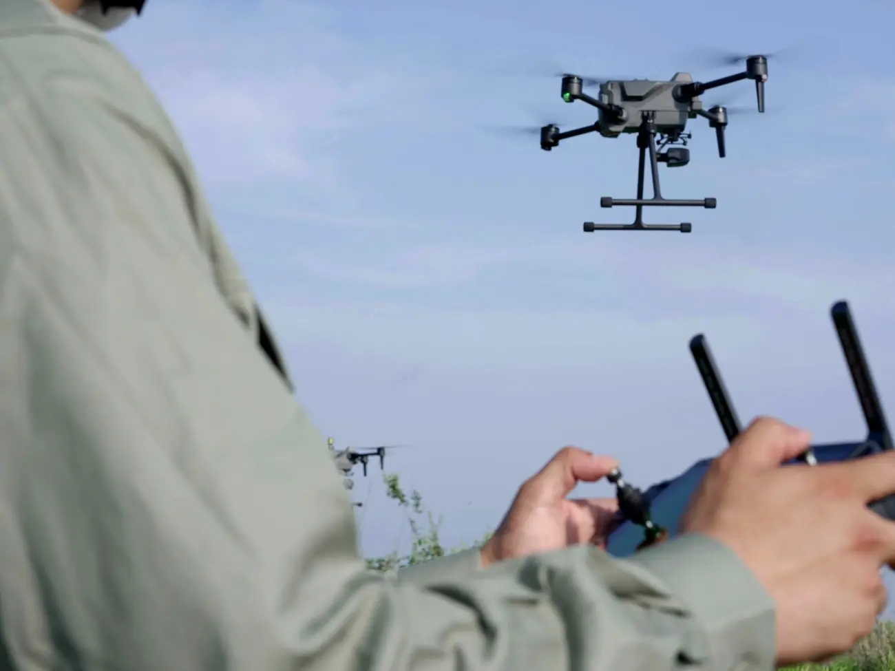 An operator holding a remote controller while an S400E drone flies overhead